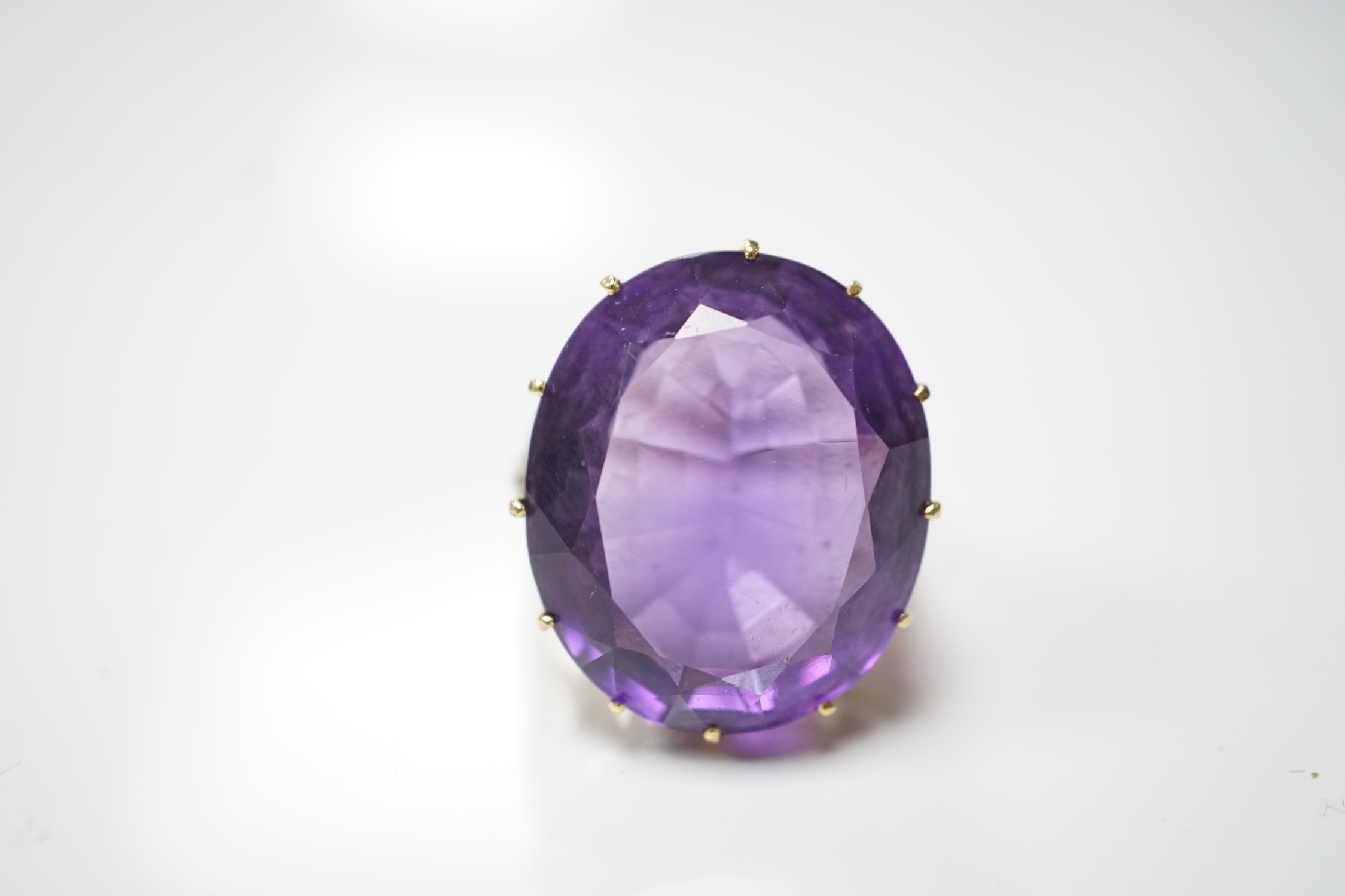 A yellow metal and oval cut amethyst set dress ring, with diamond chip set shoulders, size O, gross weight 10.6 grams.